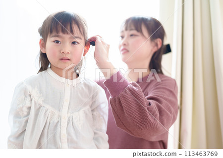 A mother styling a girl's hair A mother styling a girl's hair 113463769