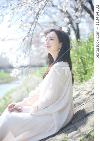 A woman enjoying cherry blossom viewing by the river A woman enjoying cherry blossom viewing by the river 113464332