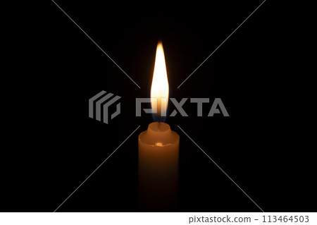 A lit candle on a dark background 113464503