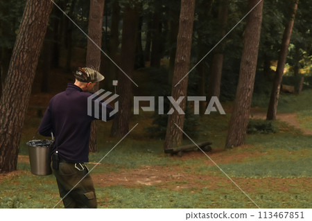 Forester collecting samples in the forest, holding a bucket, showcasing environmental conservation efforts and sustainable forestry practices. Environmental activist working in the forest 113467851