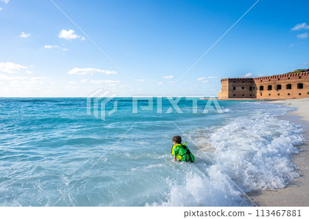 Child playing in the beach surf outside Fort Jefferson on Dry Tortugas National Park. Child playing in the beach surf outside Fort Jefferson on Dry Tortugas National Park. 113467881
