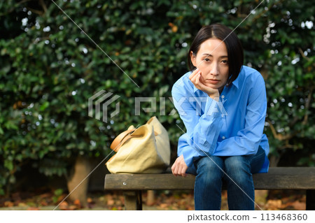 一個憂心忡忡的女人坐在長凳上 113468360