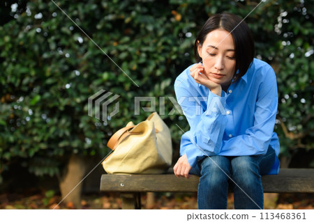 A worried woman sitting on a bench A worried woman sitting on a bench 113468361