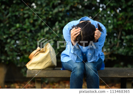一個憂心忡忡的女人坐在長凳上 113468365