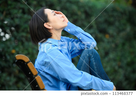 一個憂心忡忡的女人坐在長凳上 一個憂心忡忡的女人坐在長凳上 113468377