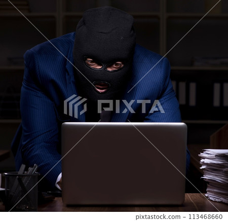 Male employee stealing information in the office night time 113468660