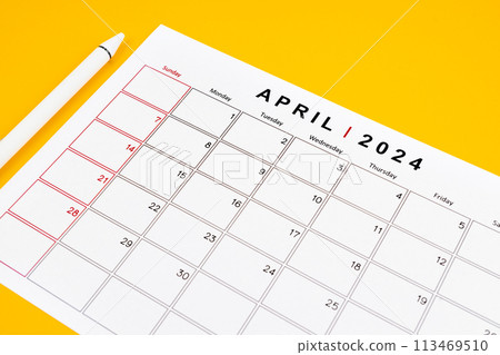 April 2024 desk calendar and pen on yellow color background. 113469510