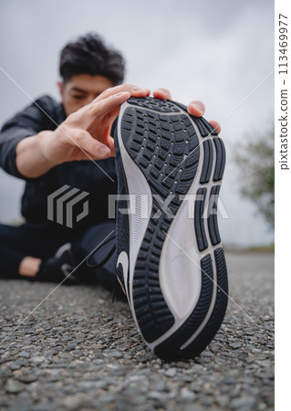 Man doing flexibility exercises outdoors Man doing flexibility exercises outdoors 113469977