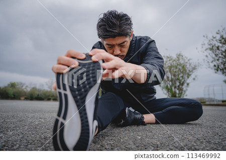 Man doing flexibility exercises outdoors Man doing flexibility exercises outdoors 113469992