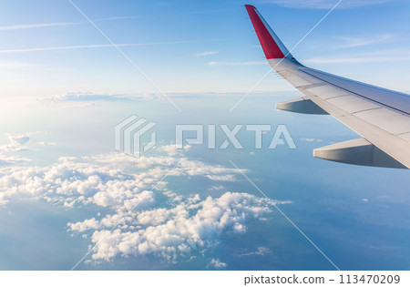 View from the airplane window at a beautiful cloudy sky and the airplane wing View from the airplane window at a beautiful cloudy sky and the airplane wing 113470209