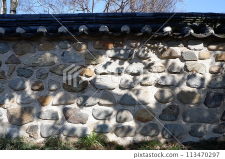 Stone wall with tiles, exterior wall of a traditional Korean house Stone wall with tiles, exterior wall of a traditional Korean house 113470297