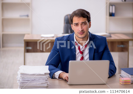 Young male employee and too much work in the office Young male employee and too much work in the office 113470614