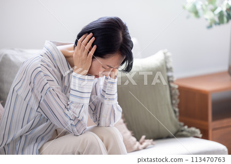 Poor health, headache, middle-aged woman holding her head 113470763