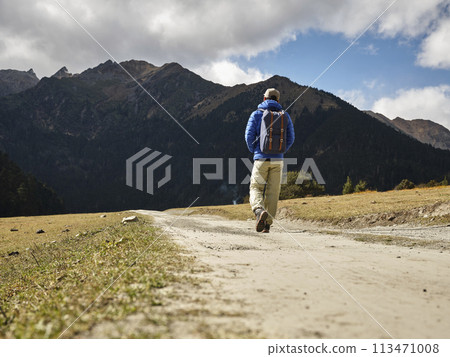 rear view of lone asian hiker walking on dirt road 113471008