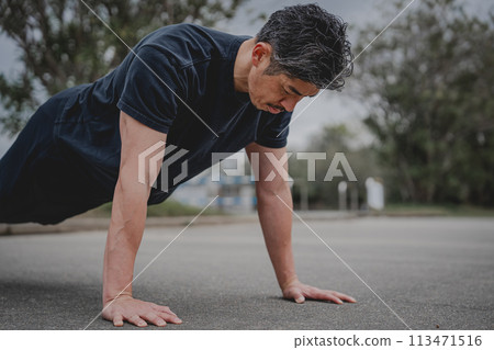 A man in his 40s doing strength training outdoors 113471516