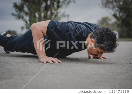 A man in his 40s doing strength training outdoors A man in his 40s doing strength training outdoors 113471519