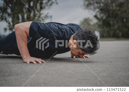 A man in his 40s doing strength training outdoors 113471522