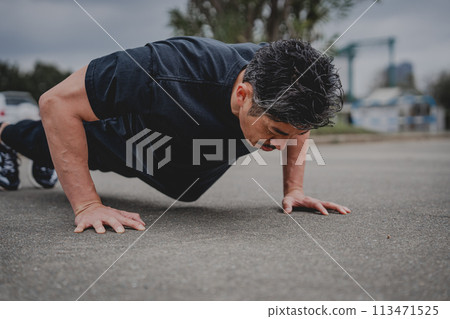A man in his 40s doing strength training outdoors 113471525