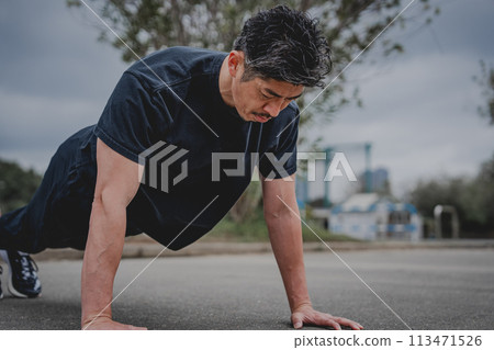 一名40多歲的男子在戶外進行肌肉訓練 一名40多歲的男子在戶外進行肌肉訓練 113471526