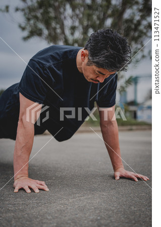 A man in his 40s doing strength training outdoors 113471527