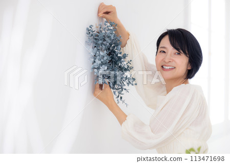 一位中年婦女拿著尤加利花環微笑 一位中年婦女拿著尤加利花環微笑 113471698