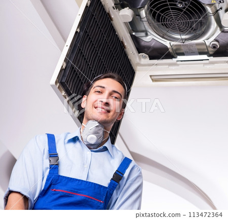 Young repairman repairing ceiling air conditioning unit Young repairman repairing ceiling air conditioning unit 113472364