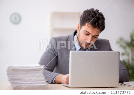 Young male employee and too much work in the office Young male employee and too much work in the office 113473772