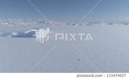Frozen iceberg in Antarctica ocean ice desert water up to horizon. Antarctic polar winter. Aerial view of iceberg locked in ice Antarctica landscape. Polar Frozen ocean covered with snow. South nature 113474057