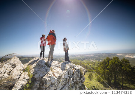 Group of People Standing on Top of a Rock 113474338