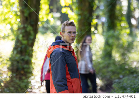 Man in Red and Black Jacket Walking Through Forest 113474401