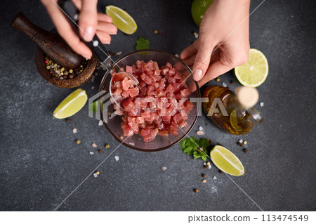 Woman mixing Sliced and chopped tuna fillet and spices in glass bowl cooking traditional tartare Woman mixing Sliced and chopped tuna fillet and spices in glass bowl cooking traditional tartare 113474549