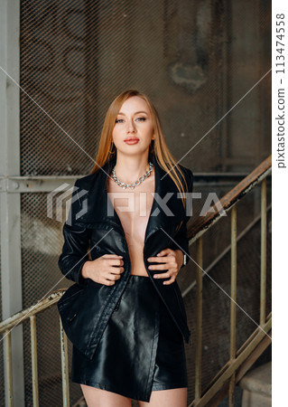 Beautiful young red-haired long-haired woman in black leather shirt 113474558