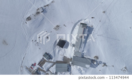 Aerial drone view flight. Vernadsky Base, ocean, mountains. Fast. The station settlement on the Antarctica continent surrounded snow covered mountains and ice ocean. Harsh conditions. 113474944