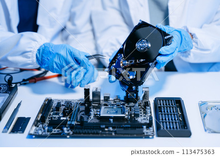 Technician repairing inside of hard disk drive by screwdriver. the concept of data, hardware, technician and technology. computer hardware, upgrade . 113475363