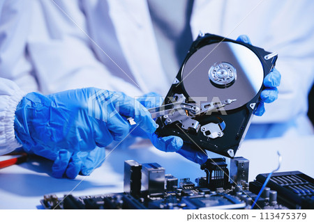 Hard disk drive on the technician's desk and a computer motherboard as a component. the concept of data, hardware. 113475379