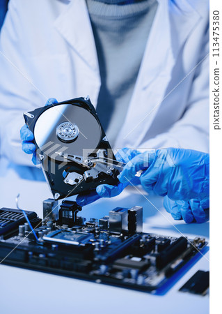 Technician repairing inside of hard disk drive by screwdriver. the concept of data, hardware, technician and technology. computer hardware, upgrade . 113475380