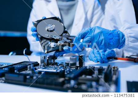 Technician repairing inside of hard disk drive by screwdriver. the concept of data, hardware, technician and technology. computer hardware, upgrade . 113475381