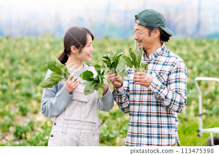 A young woman and a middle-aged man smiling while holding crops 113475398