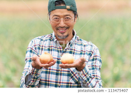 一名中年男子手裡拿著收穫的洋蔥微笑 113475407