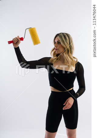 Young woman with roller brush on red white background Instruments accessories for renovation room 113476044