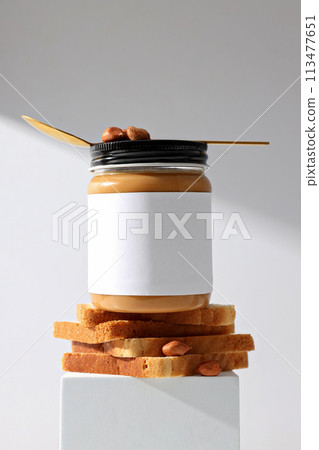 Peanut paste in a glass jar, on a light background. Peanut paste in a glass jar, on a light background. 113477651