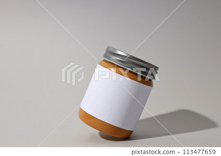 Peanut paste in a jar with a label, on a gray background. 113477659