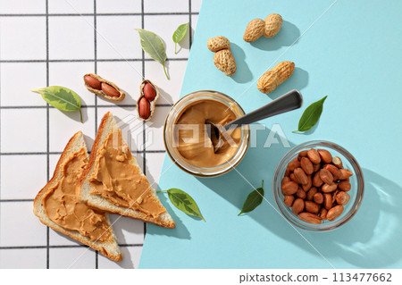 Peanut paste in a glass jar with toast, on a light background. 113477662