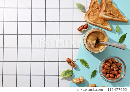 Peanut paste in a glass jar with toast, on a light background. 113477663