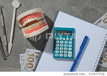 Jaw and dental instruments, calculator, cash and notepad on gray background, top view Jaw and dental instruments, calculator, cash and notepad on gray background, top view 113477730