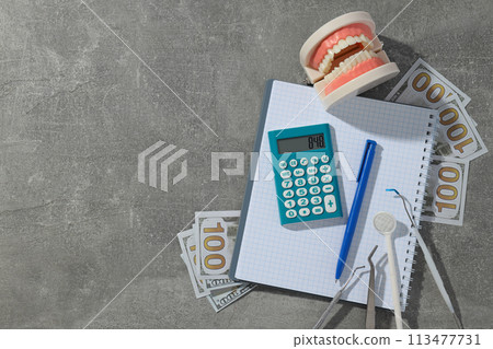 Jaw and dental instruments, calculator, cash and notepad on gray background, space for text 113477731