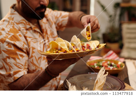 Man holding plate with Mexican tacos Man holding plate with Mexican tacos 113477918
