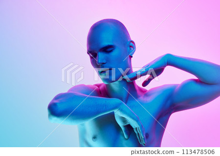Portrait of young shirtless bald man posing with gestures on gradient blue pink background in neon light 113478506