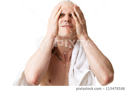 Young bald man with towel on shoulders washing face in bathroom at home isolated on white studio background. Water drops 113478586