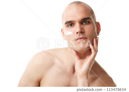 Handsome shitless young man with moisturizing cream on face isolated on white studio background. Spotless well-kept skin 113478634